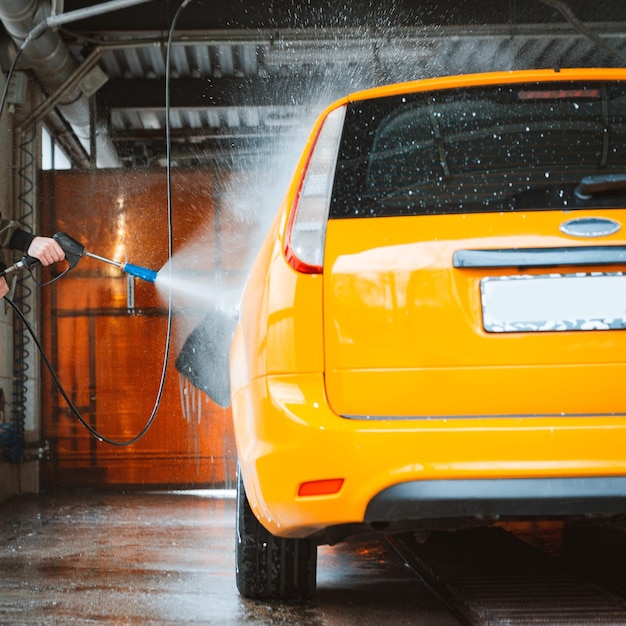 Washing a yellow car at a contactless selfservice car wash Washing a sedan car with foam and highpressure water