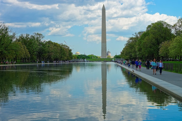 Washington D.C., USA - May 2, 2015: People are taking a walk near the pool in the National Mall, Washington D.C. The monument of the first american president George Washington is seen in the back.