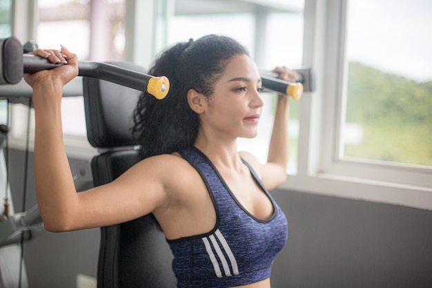 Wasit up image of a fit young African American woman working out with hand weights in a fitness gym