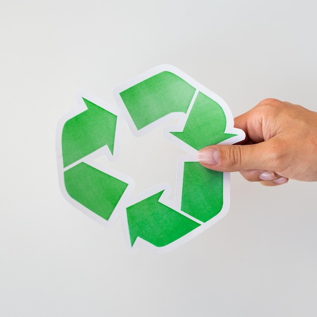 Photo waste recycling, reuse, garbage disposal, environment and ecology concept - close up of hand holding green recycle symbol