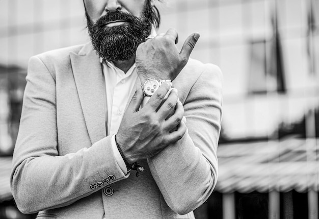 Watch in a man Businessman points to his watch on the background of the town Man holds his watch Portrait successful businessman in a business suit using the watch on a city background