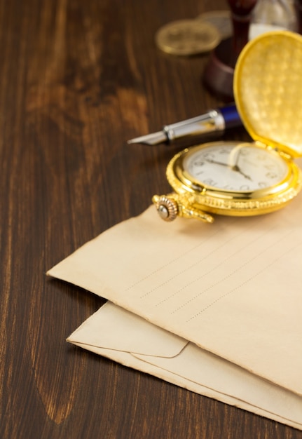 Watch and old envelope on wooden background