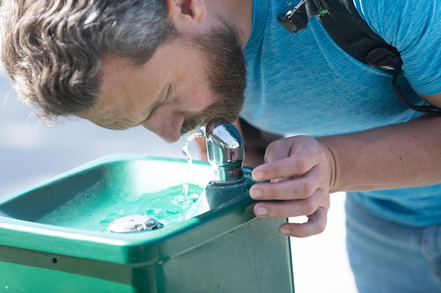 Water aid your thirst. Thirsty man. Guy drink water from drinking fountain. Thirst quenching. Feel refreshing. hydration and water balance.