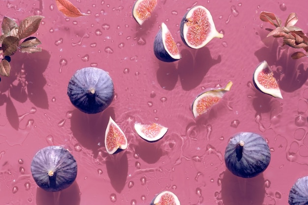 Water background with fresh ripe fig fruits and slices swimming in water Ripples water rings and drops on vibrant pink background square composition