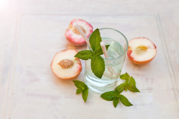 Water drink with peaches  refreshing iced tea with peppermint and peaches on grey background