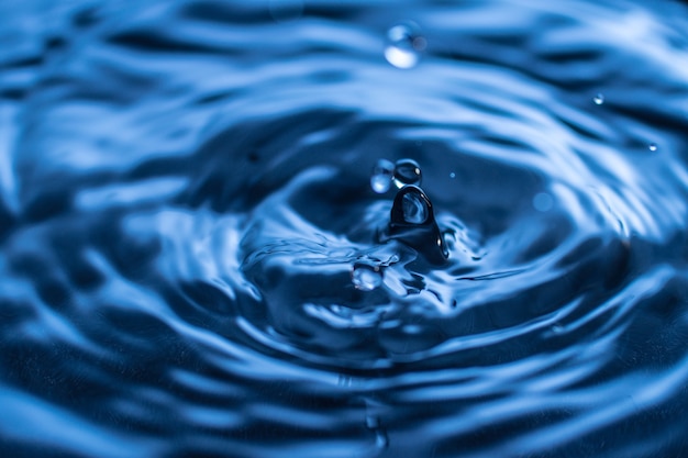 Water drop splash in a glass blue colored