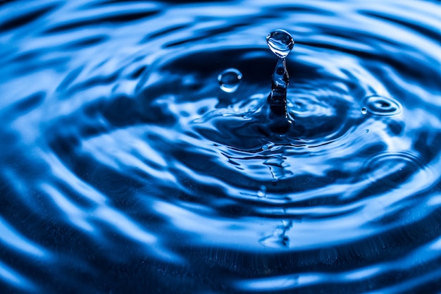 Water drop splash in a glass blue colored