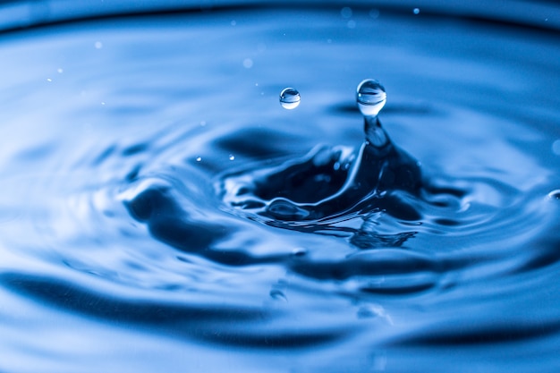 Water drop splash in a glass blue colored