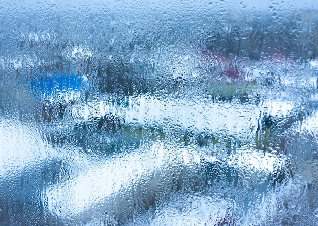 Water droplets condensation background of dew on glass humidity and foggy blank background Condensation on the glass of metalplastic window Outside the window bad weather rain