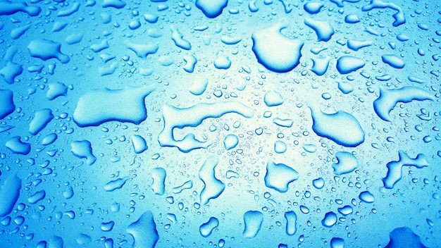 Water Drops background on the Blue glossy surface Rain droplets on blue texture for cosmetics drin