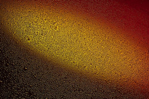 Water drops on black glass. Background illuminated with red and