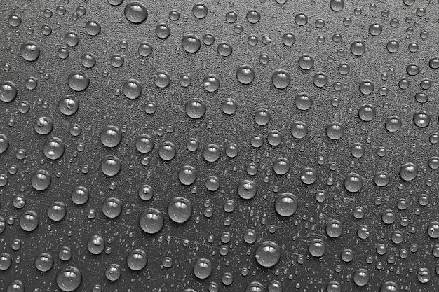 water drops on a black plastic surface. On a black background. Top view.