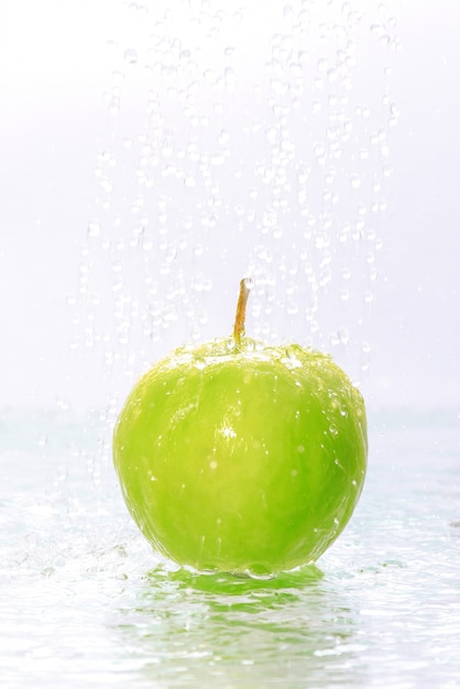 Water drops falling on green apple