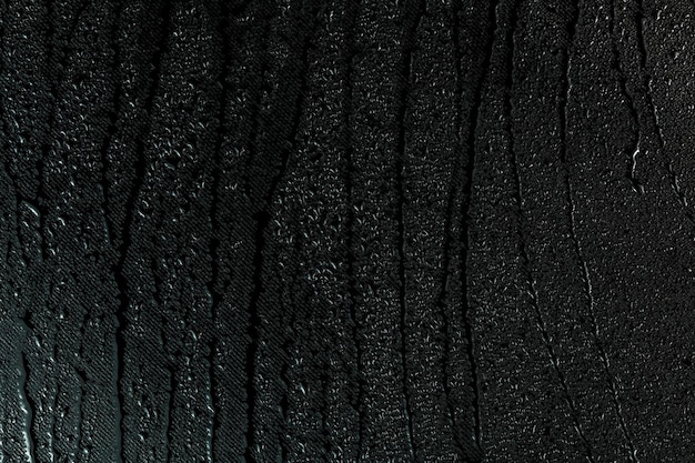 Water drops on flat black rubber surface macro background with smudges