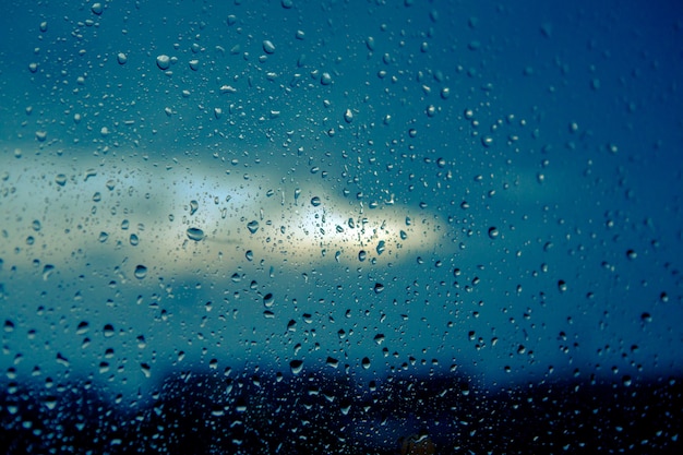 Water drops on glass against blue cloudy sky in the evening