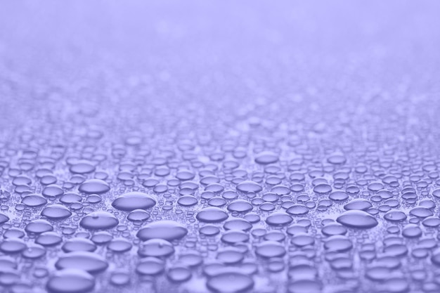 Water drops in Very peri color of the Year 2022. Violet abstract background or texture.