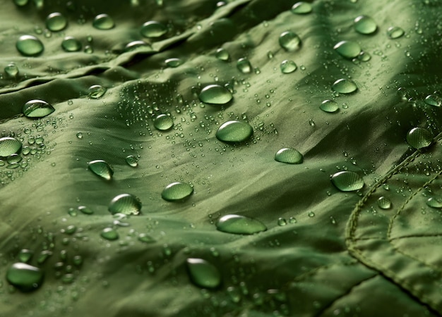 Water drops on waterproof membrane fabric. Detail view of texture of green waterproof cloth.