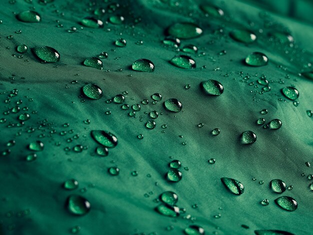 Water drops on waterproof membrane fabric. Detail view of texture of green waterproof cloth.