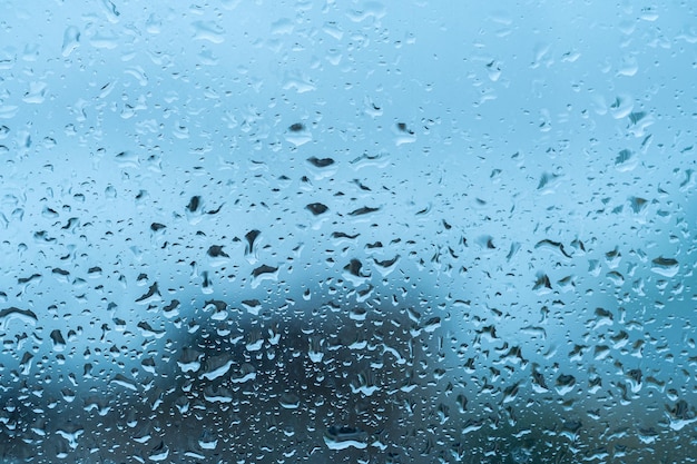 Water drops on window glass Raindrops on window Blue tone Natural water drop texture