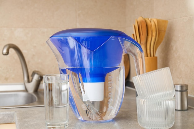 A water filter stands in the kitchen with a glass of water