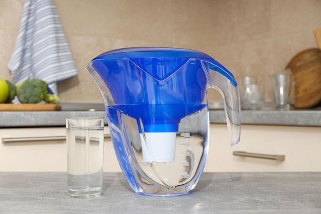 A water filter stands in the kitchen with a glass of water