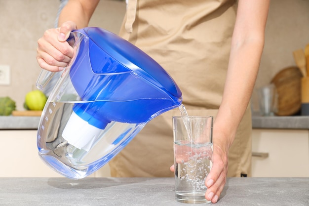 A water filter stands in the kitchen with a glass of water