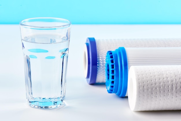 Photo water filters. carbon cartridges and a glass on a white background. household filtration system.