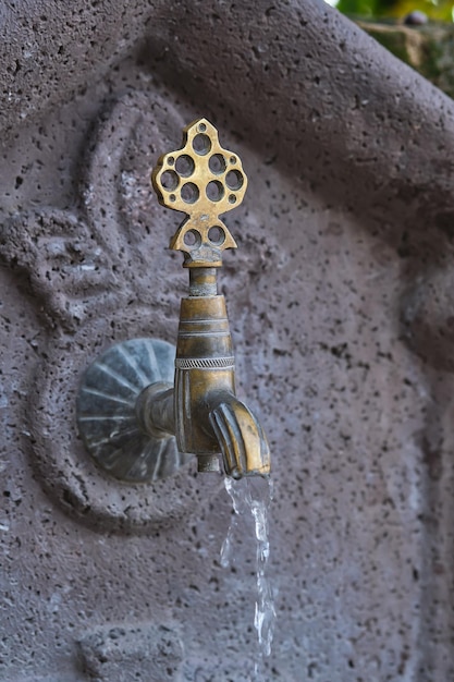 Water flows from an old copper faucet a vertical shot of a sink in a public place on the street of the old city in Turkey travel time an idea for a background