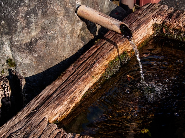 Water from streams flowing through a wooden pipe in a rural village in Japan