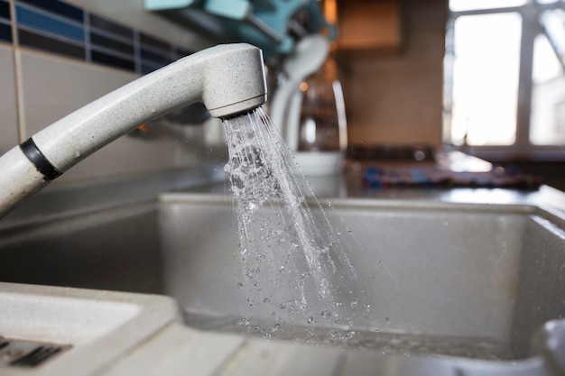 Water is pouring from a faucet Water tap on the background of the kitchen