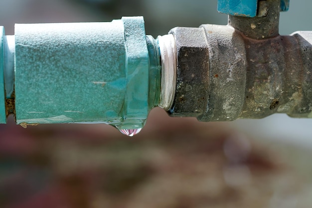 Water leaks water drop from a long-used blue plumbing pipe. Selective focus to Water leaks.