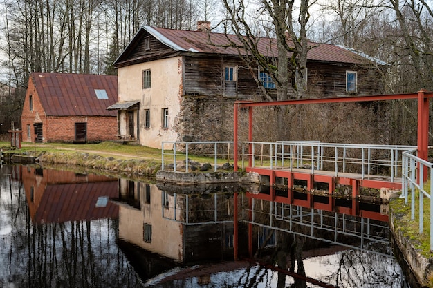 Water mill on the shore of lake and its reflection on the surface of the water