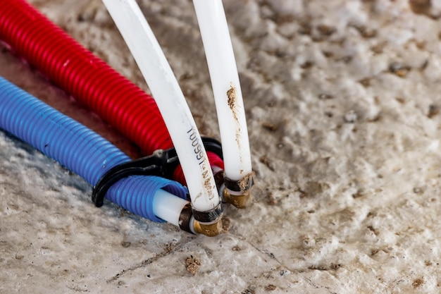 Photo water pipes corrugated in red and blue plumbing system in the floor pipe laying on the floor of the house