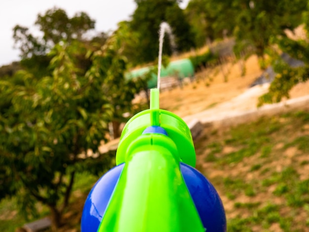 Water pistol shooting a dispersion of water in first person towards the garden at sunset and the mountains in the background