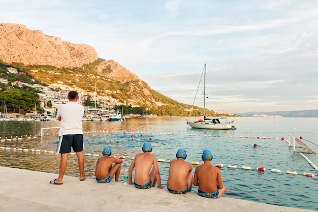 Water polo reserve players and trainer watching the match in Omis, Croatia