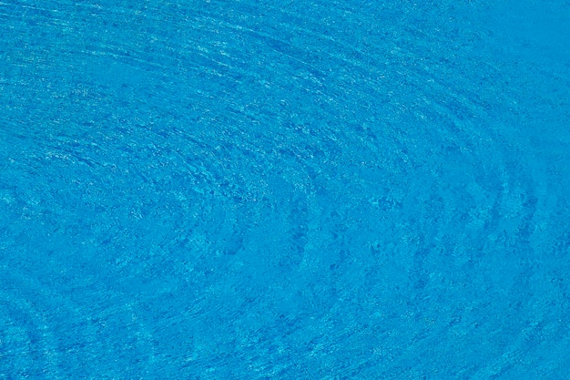 Water ripples on blue tiled swimming pool background View from above