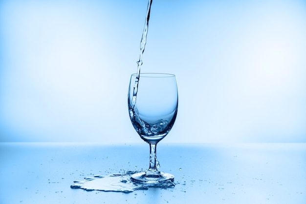 Water splash collection in wine glass isolated on blue