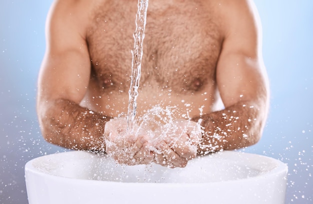 Water splash hands and man in studio for skincare wellness or cleaning on blue background Hand palm and skin male model relax in luxury gentle or moisture or beauty cosmetic treatment isolated