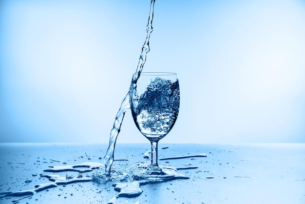 Water splashing from glass isolated on blue background