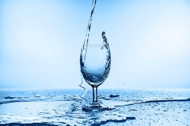 Water splashing from glass isolated on blue