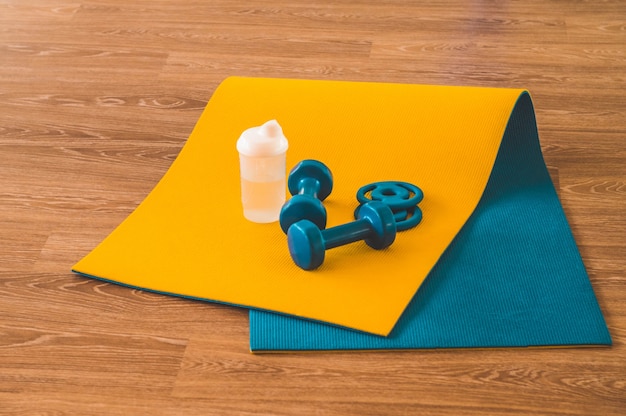 Water, sports blue dumbbells at  sports mat in the gym