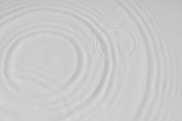 Water tranquil ripple background. Water texture, circles and bubbles on a liquid white surface. Cosmetic products and flat design concept. High quality photo