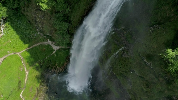 A waterfall in the forest with a green field in the background