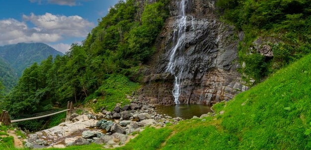 a waterfall is in the background of a green mountain