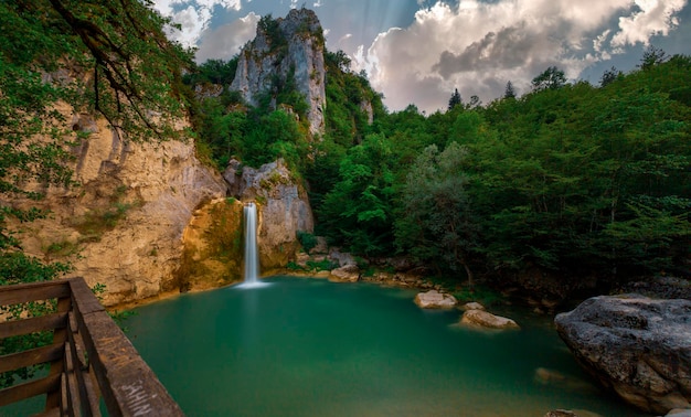 a waterfall in the middle of a forest with a waterfall in the background