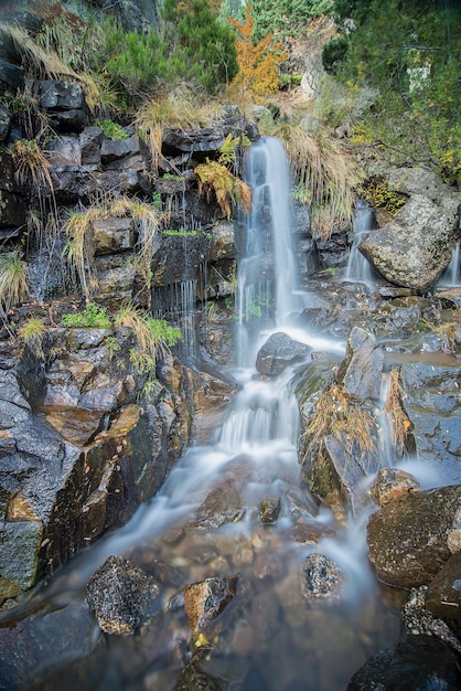 Waterfall with blue tones, with green vegetation, in the black lagoon of Soria, Spain