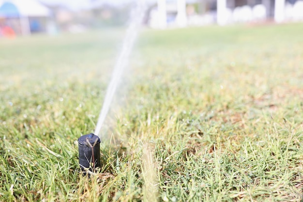 A watering tap irrigates the grass of the lawn blurry