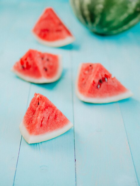 Watermelon background. Side view of watermelon slices on blue wooden tabletop. Copy space for text. Vertical. Toned image