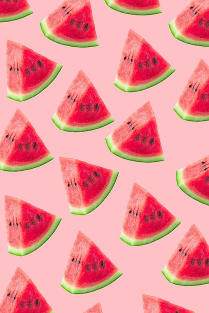 Watermelon cut into small pieces with shell are arranged on pink background