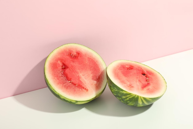 Watermelon halves on white and pink two tone background